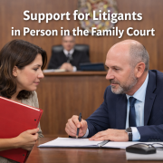 A McKenzie Friend supporting a litigant in person during a family court hearing by reviewing documents together.