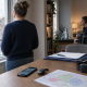 Person looking out of a window while a headset-wearing colleague works at a desk with maps and tracking devices nearby